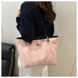 Detail of pink pleated tote bag showing large capacity and black contrast handle on model