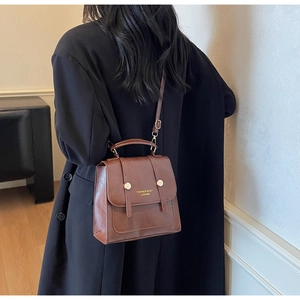Rear view of model wearing a vintage brown leather backpack with gold metal details