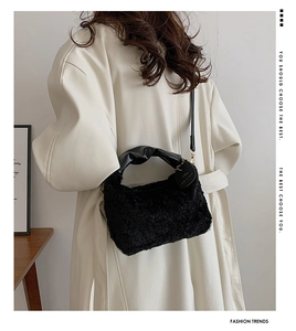Detail of black plush handbag with ruffled leather handle and 'YOU' pendant charm