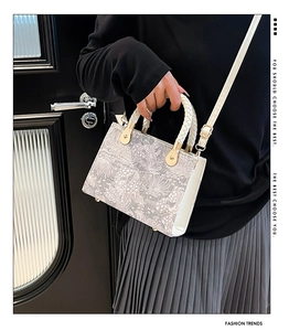 Close-up of structured handbag with grey jacquard floral texture and woven handles