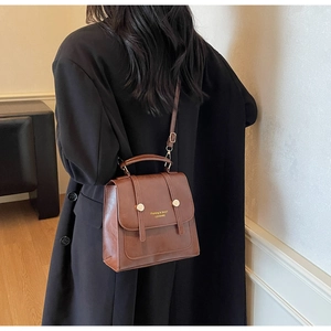 Close-up of vintage brown PU leather backpack with gold buckles and embossed lettering