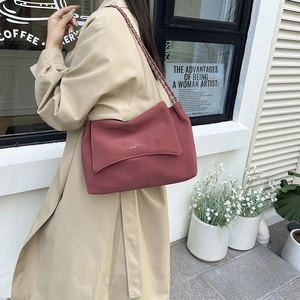 Minimalist dark pink leather tote bag with chain strap worn by a model in khaki coat