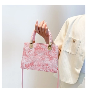 Detail of pink floral jacquard fabric texture and braided handles on stylish crossbody bag