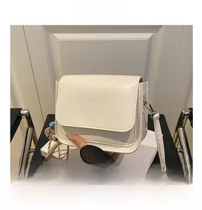 Détail du sac bandoulière blanc avec gaufrage chat 3D et breloque ours en peluche