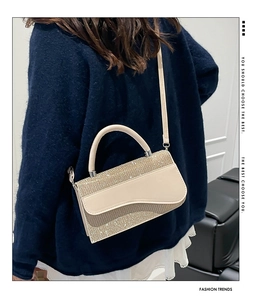 Detailed back view of a beige sequin crossbody bag showing the wave-cut flap on a model