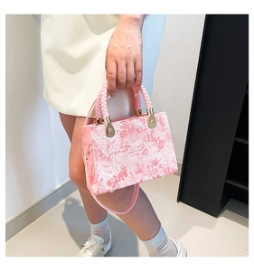 Detail of pink floral jacquard tote bag featuring woven handles and gold hardware accents