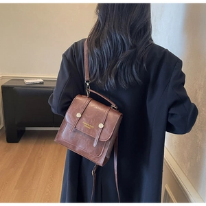 Close-up of brown vintage PU leather backpack featuring metal buckles and gold lettering