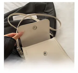 Détail du sac bandoulière blanc crème avec fermeture magnétique et boucles métalliques