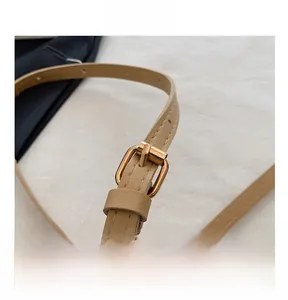 Macro shot of adjustable beige faux leather shoulder strap with gold metal buckle detail