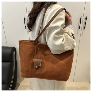 Detail of brown suede tote bag with slim straps and mini pouch on model in trench coat