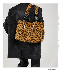 Detail of leopard print tote bag with gold chain strap and pearl accents on model