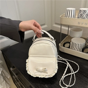 Detailansicht eines cremefarbenen Mini-Rucksacks mit Spitzenbesatz und Kettengurt