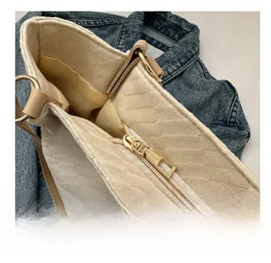 Close-up of premium gold-tone zipper and quilted texture on a beige tote bag