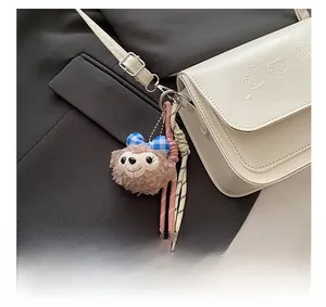 Détail d'un pendentif ours en peluche avec nœud sur un sac en cuir blanc texturé