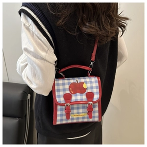 Vue arrière du mannequin portant un mini sac à carreaux bleus avec motif pomme rouge