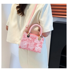 Detail view of pink crossbody bag with intricate white patterns and round handles
