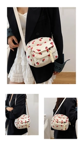 Detailed view of white corduroy crossbody bag with cute red strawberry patterns and pocket
