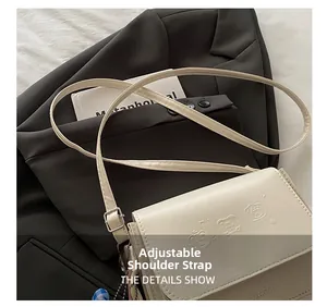Détail de la bandoulière réglable avec boucle argentée sur un sac bandoulière beige