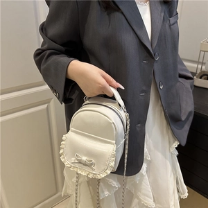 Detailansicht der weißen Mini-Handtasche mit beigem Spitzenbesatz und süßer Schleife