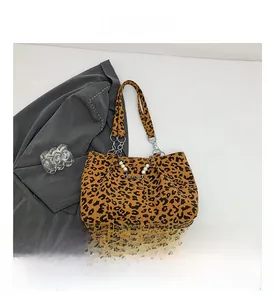 Detail view of leopard print tote bag with pearl heart chain and metal link handles