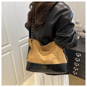 Detail of the quilted brown suede tote bag with chain strap and brand logo