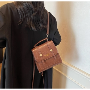 Close-up of retro brown leather bag with golden letter print and metallic magnetic buckles