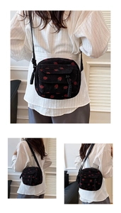 Detail view of corduroy crossbody bag with strawberry print and rope shoulder strap
