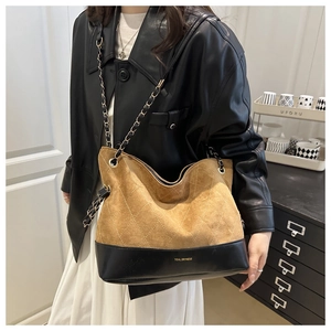 Detail of quilted leather tote featuring brown suede contrast and chain shoulder strap