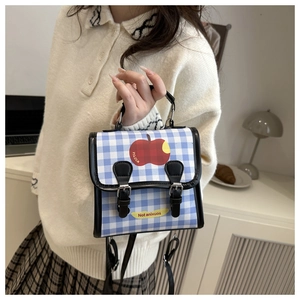 Détail du sac à main à carreaux bleus avec motif pomme et boucles en cuir noir élégantes
