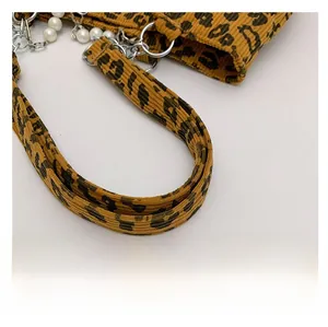 Close-up of leopard print corduroy tote with pearl chain and metallic ring detail