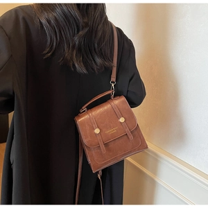 Detailed view of brown PU leather vintage messenger bag with gold rivet and logo