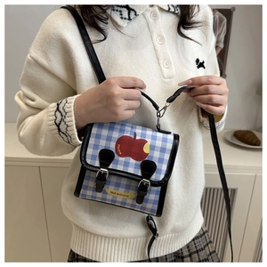 Détail du mini sac à carreaux bleus avec motif pomme et bandoulière en cuir noir