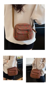 Detail of corduroy crossbody bag featuring red strawberry prints and woven zipper pull