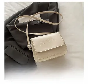 Détail du sac à bandoulière crème avec motif d'ours en relief et logo sur similicuir PU