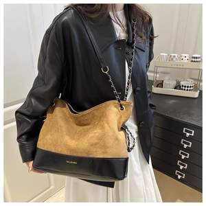Close-up of brown quilted suede tote bag with black leather base and metal chain strap