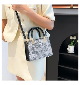 Detail of vintage square handbag with black and white floral prints and gold hardware