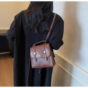 Detailed view of brown leather backpack texture with golden buckles and embossed logo