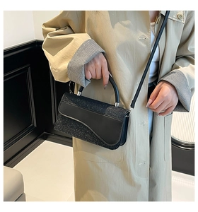 Détail du sac bandoulière pailleté noir avec rabat ondulé et poignée rigide