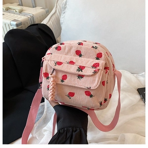 Detail of pink corduroy crossbody bag featuring cute strawberry prints and front flap pocket