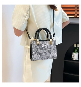 Detail of artistic floral tote bag with black woven handles and gold metal accents