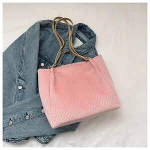 Close-up of pink tote bag with textured diamond pattern and brown shoulder straps