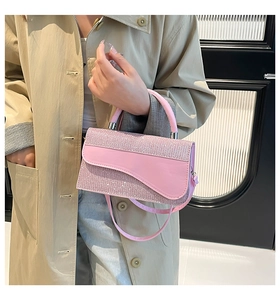 Detail view of pink glitter saddle bag with curved flap and textured rhinestone finish