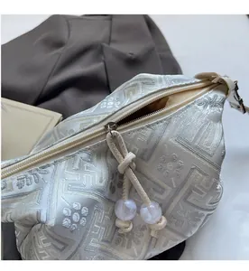 Détail d'un sac en tissu blanc cassé avec texture géométrique et perles de zip