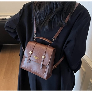 Detail of vintage brown faux leather backpack with vertical straps and gold hardware