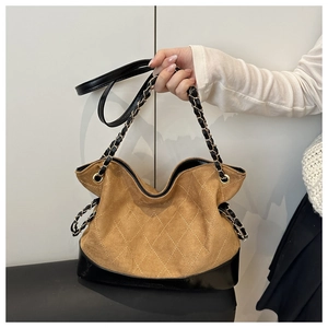 Detail view of retro diamond quilted tote with brown suede and black leather patchwork