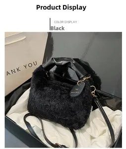 Détail d'un sac à main noir en peluche avec poignées en cuir et chaîne dorée sur tissu