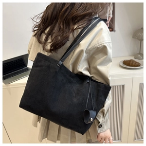 Detail of matte black suede tote bag with slim shoulder straps and matching mini pouch