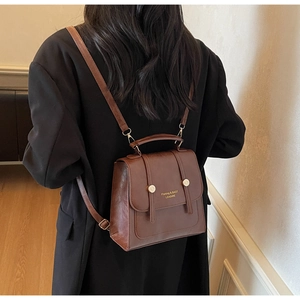 Brown PU leather backpack with flap design and gold hardware worn by female model