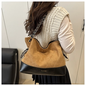 Detail of quilted camel suede tote bag with black leather base and chain strap