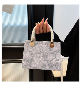 Detail of grey floral jacquard fabric bag with white woven handle and gold hardware